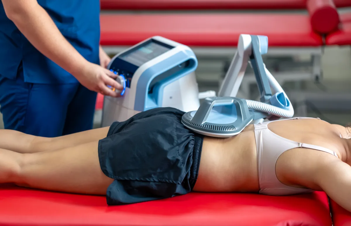 Clinician operating a CoolSculpting console while an applicator is fitted to a patient's abdomen