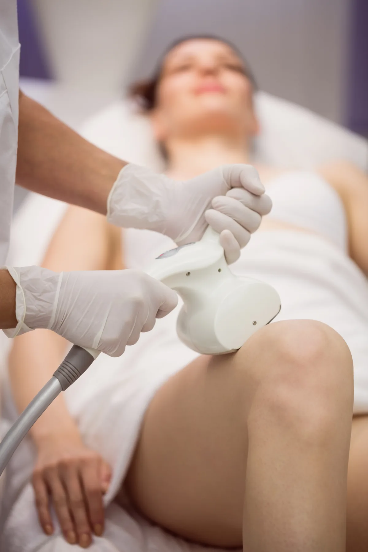 Gloved clinician gliding a radiofrequency handpiece across a patient's thigh